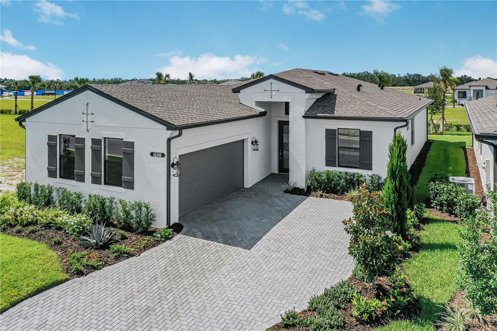 A single-story white house with a gray roof, dark shutters, and a paved driveway — 14366 HAMMOCK OAK STREET, PARRISH, FL