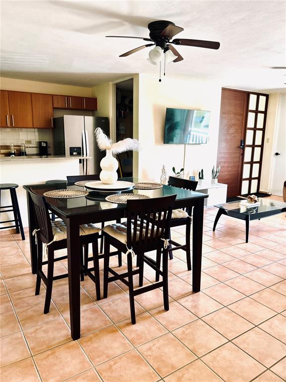 A dining area with a glass-topped table and chairs sits before an open kitchen — 187 SECTOR EL MARTILLO, BARRIO MEDIANIA ALTA UNIT F-304, LOIZA, PR