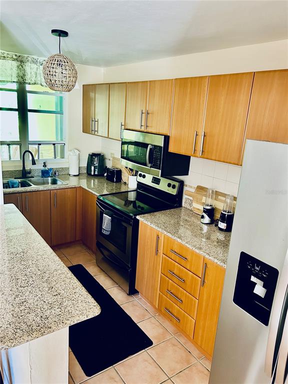A kitchen features light wood cabinets, granite countertops, stainless steel appliances, and tile flooring — 187 SECTOR EL MARTILLO, BARRIO MEDIANIA ALTA UNIT F-304, LOIZA, PR