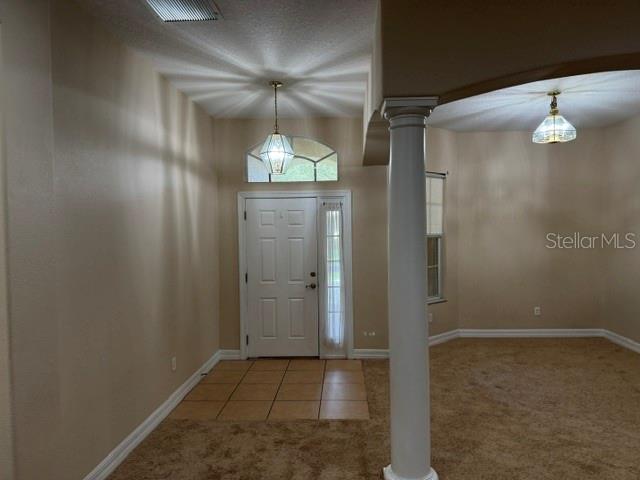 An entryway features a white front door, tile flooring, a column, and beige carpeting — 4697 BIRCHFIELD LOOP, SPRING HILL, FL