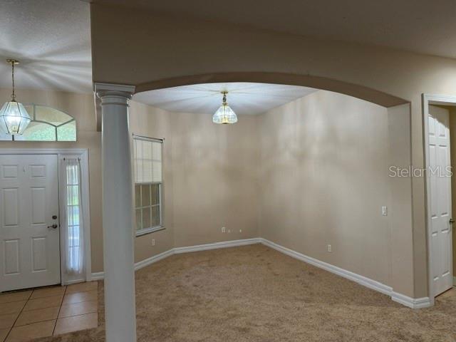An interior view shows a carpeted room with an arched entryway, a column, and two light fixtures — 4697 BIRCHFIELD LOOP, SPRING HILL, FL