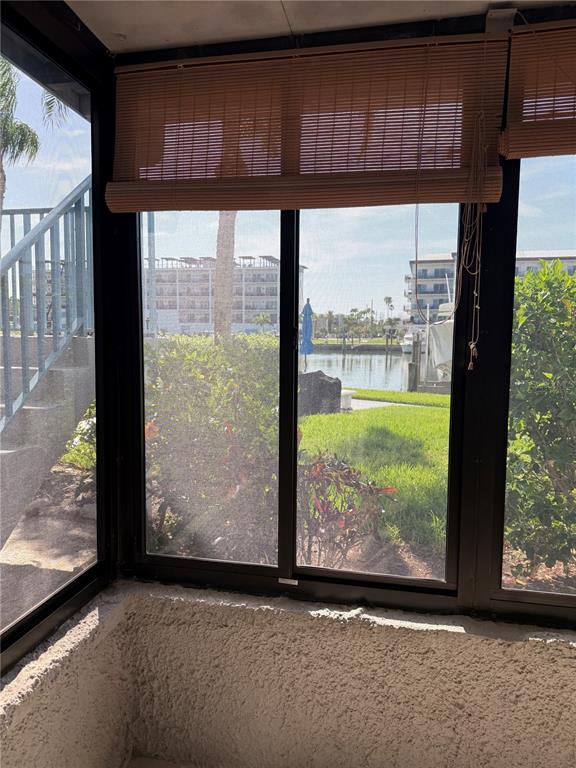 A view through a screened-in porch window looking out toward a canal and buildings — 179 MEDALLION BOULEVARD UNIT D, MADEIRA BEACH, FL