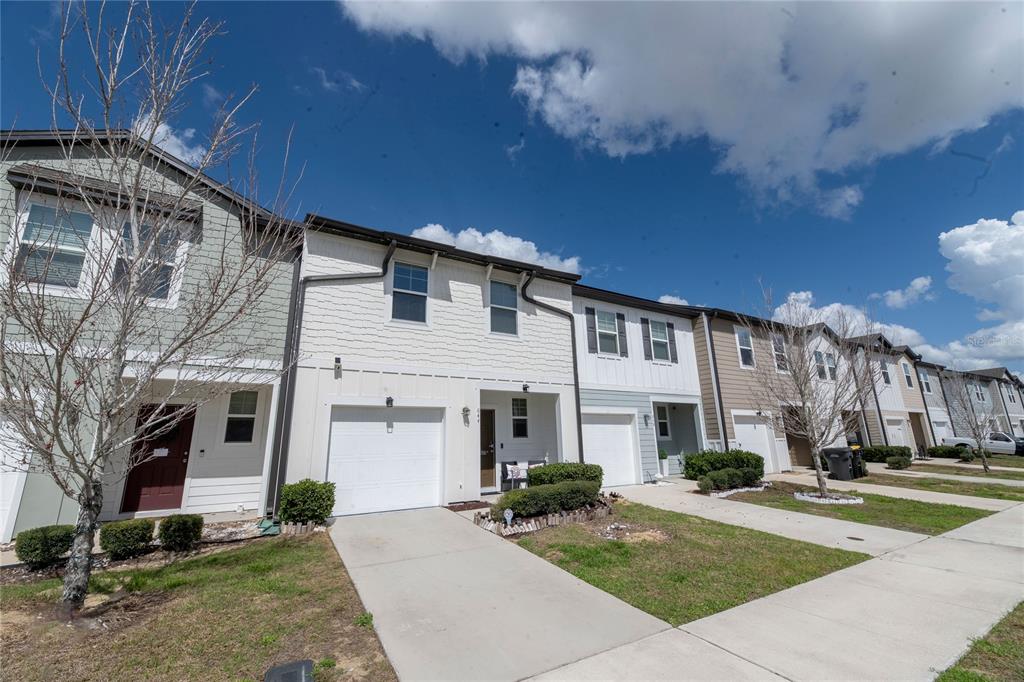 A row of modern two-story townhomes with attached garages and concrete driveways under a blue sky — 844 GRANDIN STREET, DAVENPORT, FL