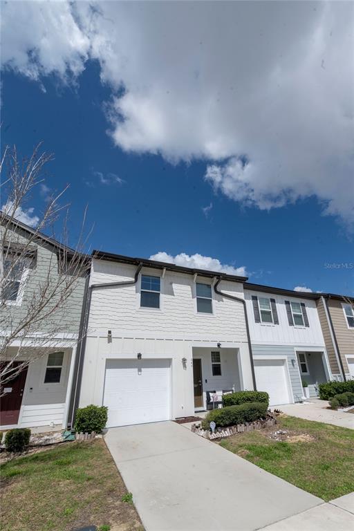A two-story townhouse with a white garage, light siding, and a concrete driveway — 844 GRANDIN STREET, DAVENPORT, FL
