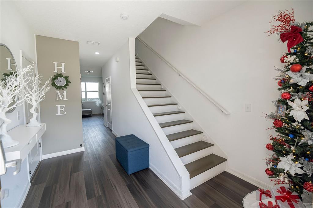 An entryway features a staircase, wood-look flooring, a "HOME" wall sign, and a decorated Christmas tree — 844 GRANDIN STREET, DAVENPORT, FL