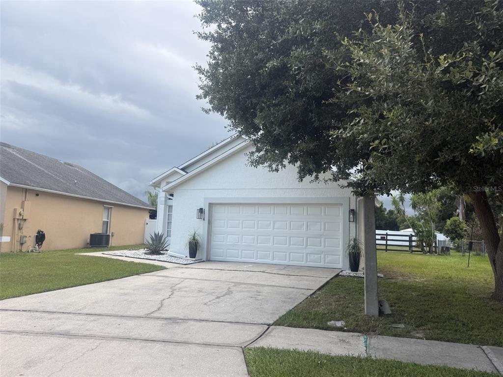 A view of a paved suburban street with a crosswalk, trees, and utility poles — 2916 CANOE CIRCLE, ST CLOUD, FL