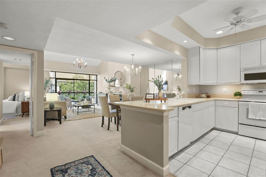 An open-concept living and dining room with a fireplace, vaulted ceilings, and a balcony view — 300 CAROLINA AVENUE UNIT 402C, WINTER PARK, FL