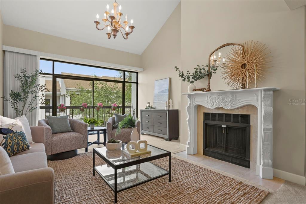 A kitchen with white cabinets and tile flooring overlooks a carpeted living area with a fireplace — 300 CAROLINA AVENUE UNIT 402C, WINTER PARK, FL