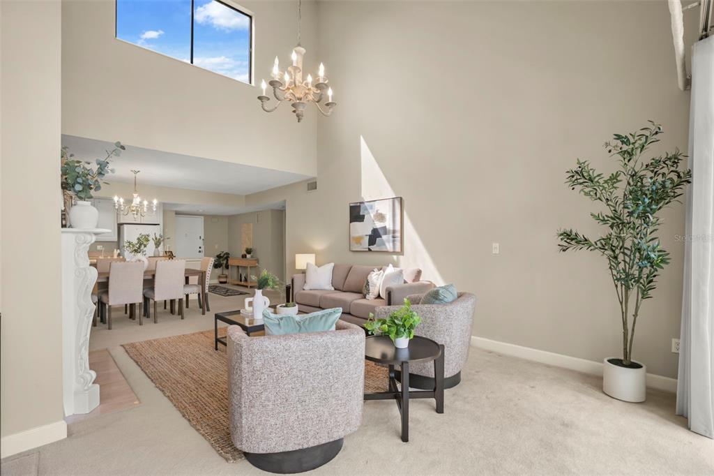 A living room with a vaulted ceiling, fireplace, carpeted floors, and a mirrored wall — 300 CAROLINA AVENUE UNIT 402C, WINTER PARK, FL