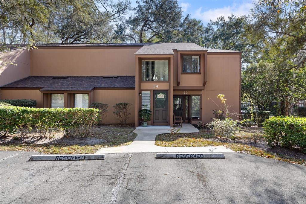A two-story brown townhouse exterior features two reserved parking spaces in the foreground — 24 FAIRWAYS CIRCLE UNIT 24, PALM COAST, FL