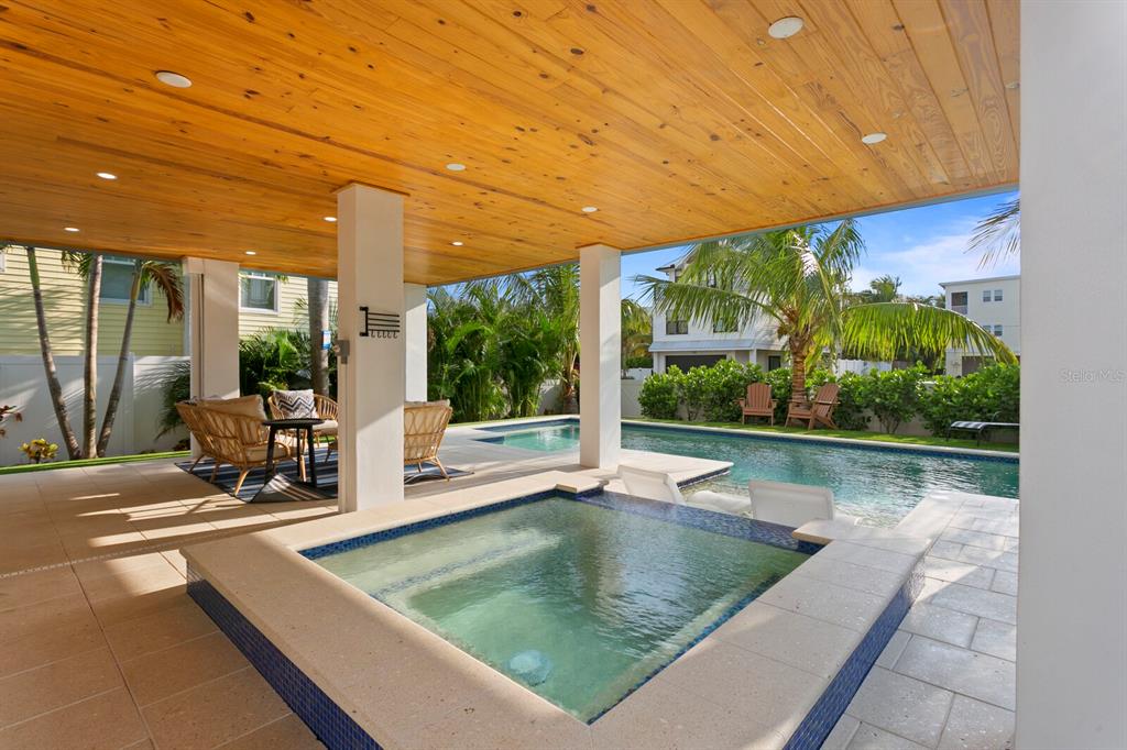 A covered patio features a hot tub, a swimming pool, and wood-paneled ceilings — 2203 AVENUE B, BRADENTON BEACH, FL