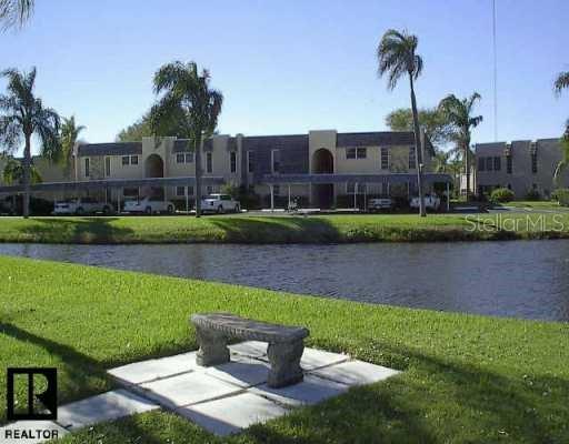 A stone bench sits on a concrete pad overlooking a pond in front of apartment buildings — 112 ELMWOOD CIRCLE UNIT 112, SEMINOLE, FL