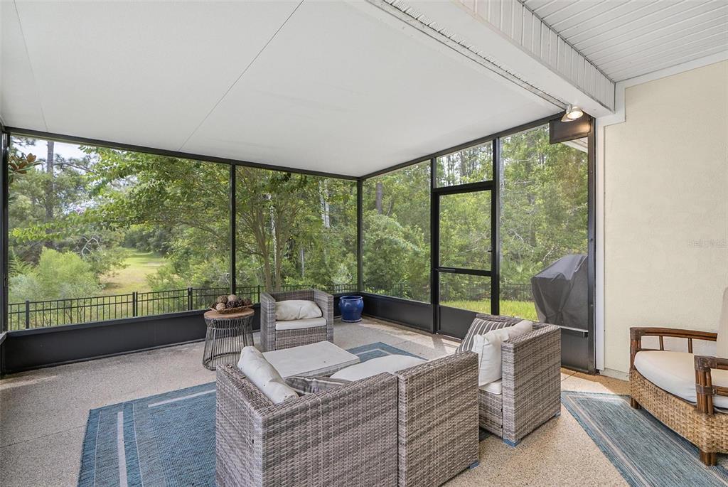 A screened-in patio features wicker furniture, a concrete floor, and a view of trees — 88 BIRDIE WAY, BUNNELL, FL