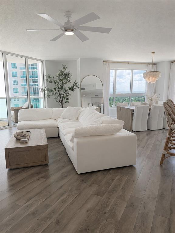 A bright living and dining area features a white sectional sofa, wood coffee table, and floor-to-ceiling windows — 241 RIVERSIDE DRIVE UNIT 2009, HOLLY HILL, FL