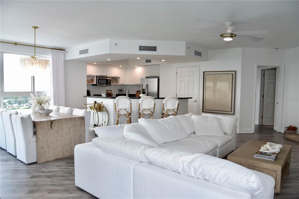 An open-concept living and dining area features a white kitchen, light wood tables, and white furniture — 241 RIVERSIDE DRIVE UNIT 2009, HOLLY HILL, FL