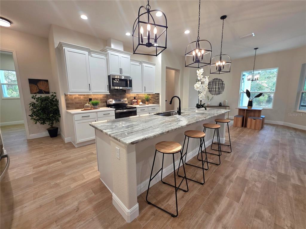 A covered front porch features two chairs, a small table, and white columns on brick bases — 13444 REPUBLICAN WAY, BROOKSVILLE, FL