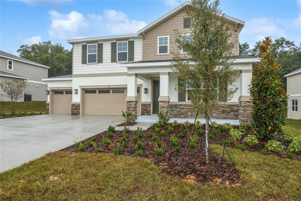 A two-story suburban house with a stone-accented facade, a three-car garage, and a front porch — 741 WEKIVA RIDGE DRIVE, MOUNT DORA, FL