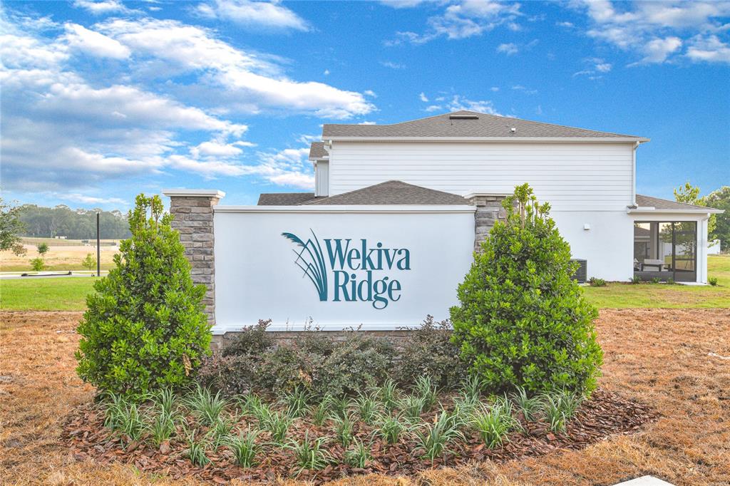 A white community entrance sign for Wekiva Ridge stands in front of a suburban house — 741 WEKIVA RIDGE DRIVE, MOUNT DORA, FL