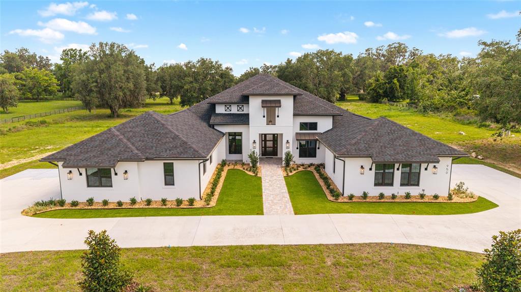 A modern white house with a dark shingled roof sits on a large grassy lot — 950 SE 80TH STREET, OCALA, FL
