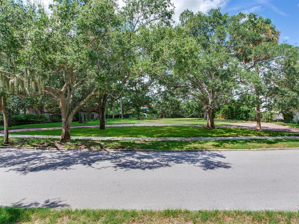 A brick driveway curves through a grassy yard shaded by large, mature oak trees — 5001 S SHORE CREST CIRCLE, TAMPA, FL