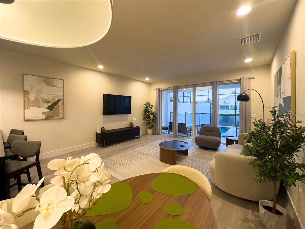 A living room features a television, a coffee table, and sliding glass doors to a patio — 17422 SERENIDAD BOULEVARD, CLERMONT, FL