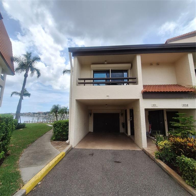 A two-story townhouse exterior features a ground-level garage, a second-floor balcony, and waterfront views — 132 1ST STREET E UNIT 101, TIERRA VERDE, FL