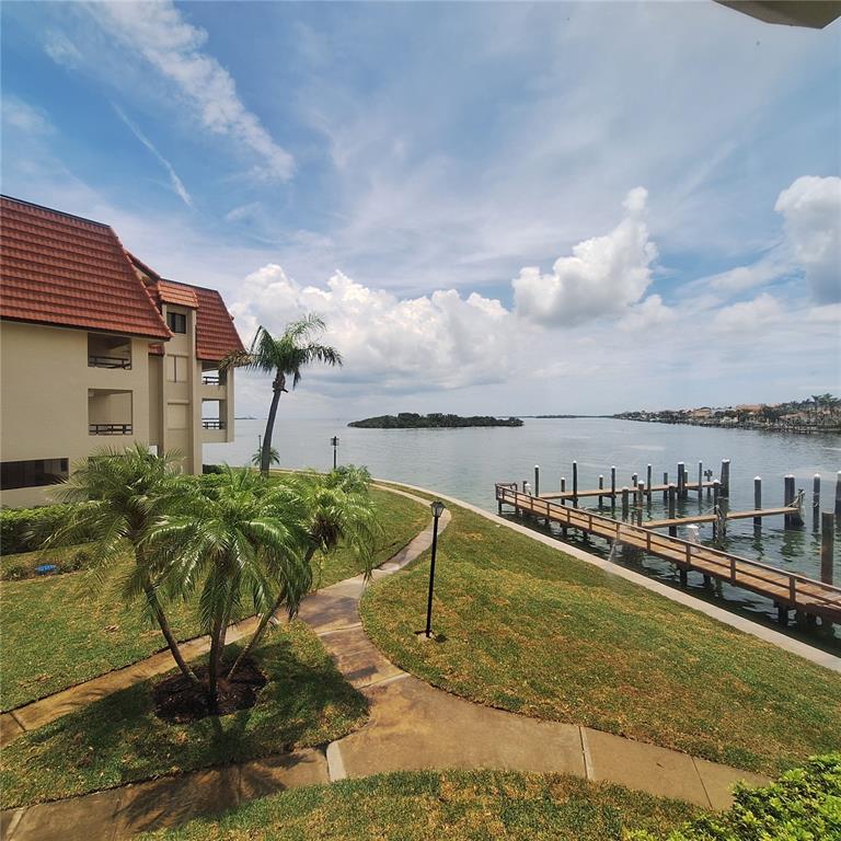 An exterior view of a waterfront building with a wooden dock and palm trees — 132 1ST STREET E UNIT 101, TIERRA VERDE, FL