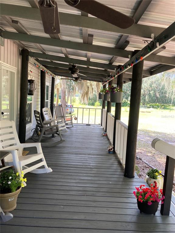 A covered porch features a white front door, rocking chairs, and a vertical welcome sign — 601 PURVIS ROAD, SEVILLE, FL