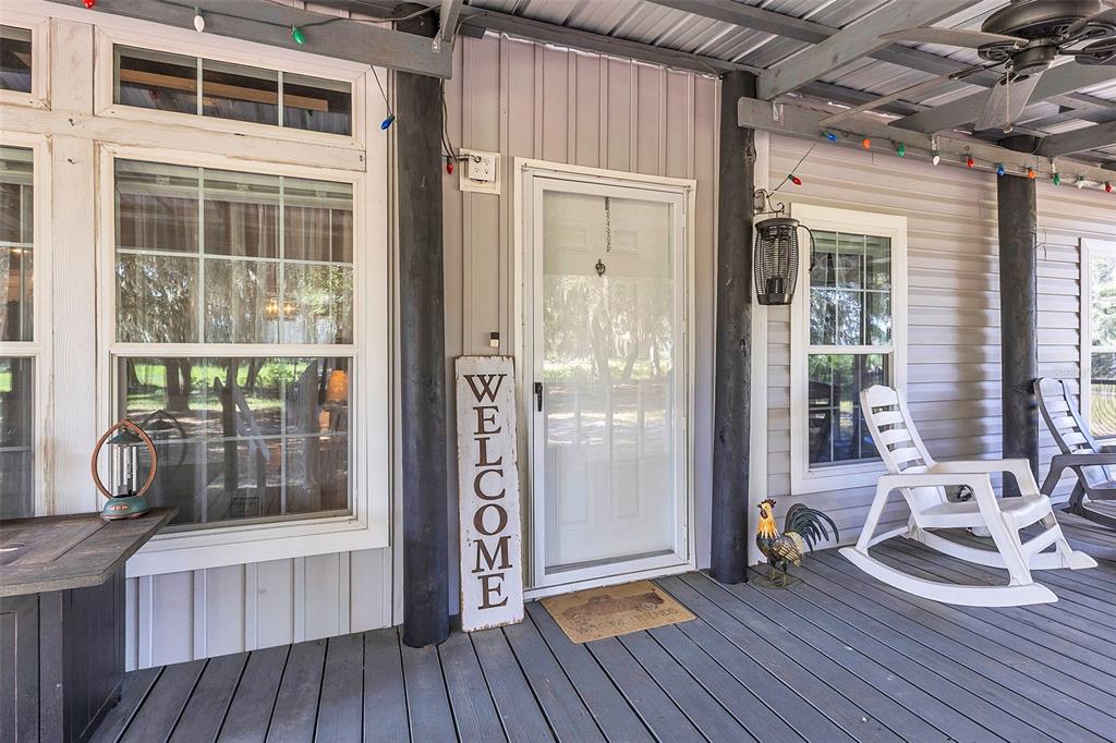 A living room features a white bookshelf, two plaid armchairs, and a coffered wood ceiling — 601 PURVIS ROAD, SEVILLE, FL