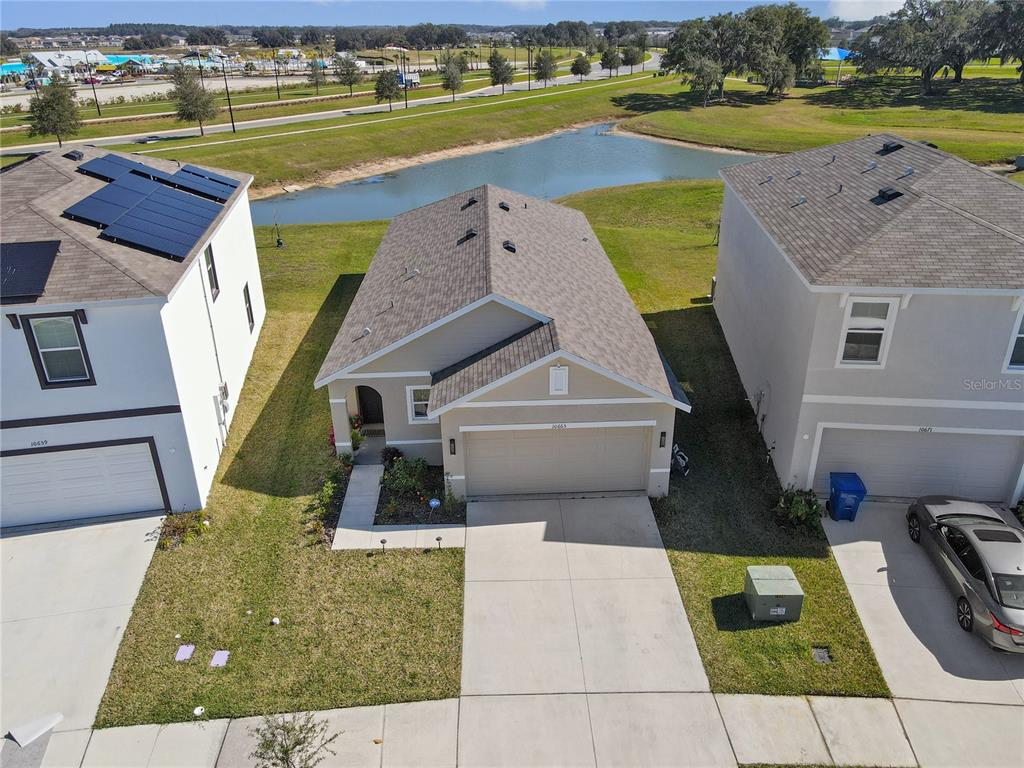 An aerial view shows a single-story house with a tan exterior and a two-car garage — 10665 PENNY GALE LOOP, SAN ANTONIO, FL