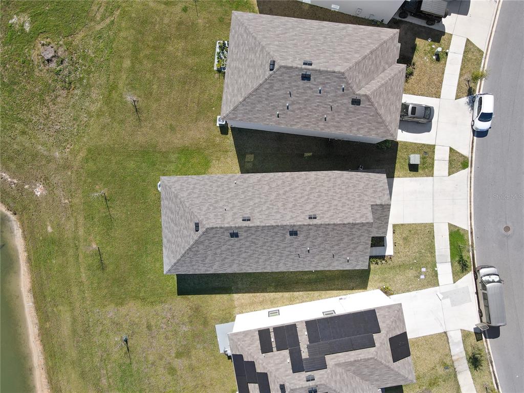 An aerial view shows three suburban houses with driveways and a nearby pond — 10665 PENNY GALE LOOP, SAN ANTONIO, FL