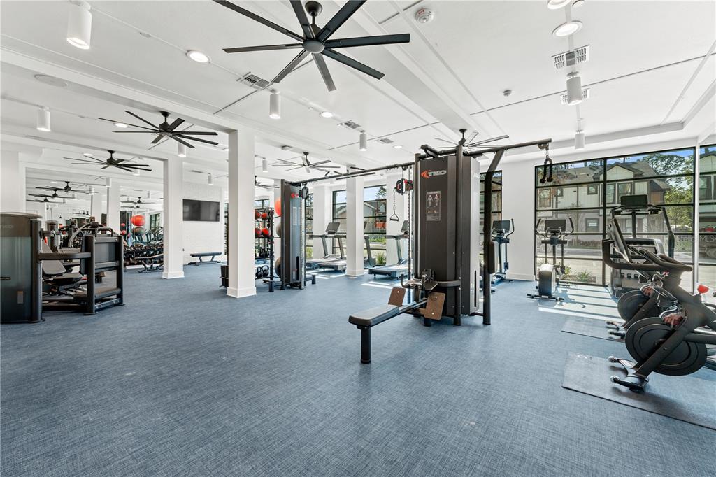 A modern fitness center features multiple exercise machines, ceiling fans, and large windows — 2285 CROWN VILLAGE ROAD UNIT A1.S, OCOEE, FL