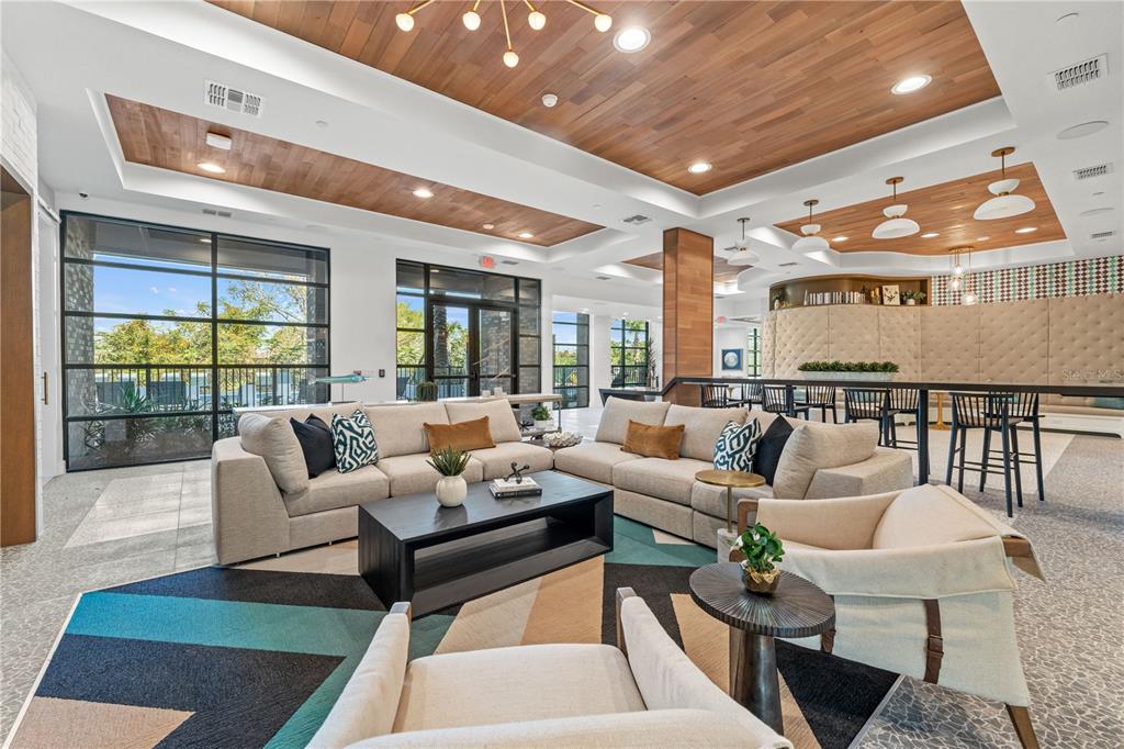 A modern lounge area features a wood-paneled ceiling, large windows, and contemporary furniture — 2285 CROWN VILLAGE ROAD UNIT A1.S, OCOEE, FL