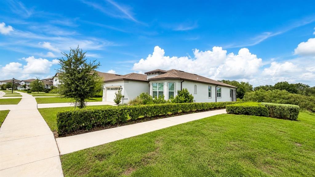 A single-story house with a light-colored exterior, a garage, and a manicured hedge — 957 SILVERLAKE BOULEVARD, LAKE ALFRED, FL