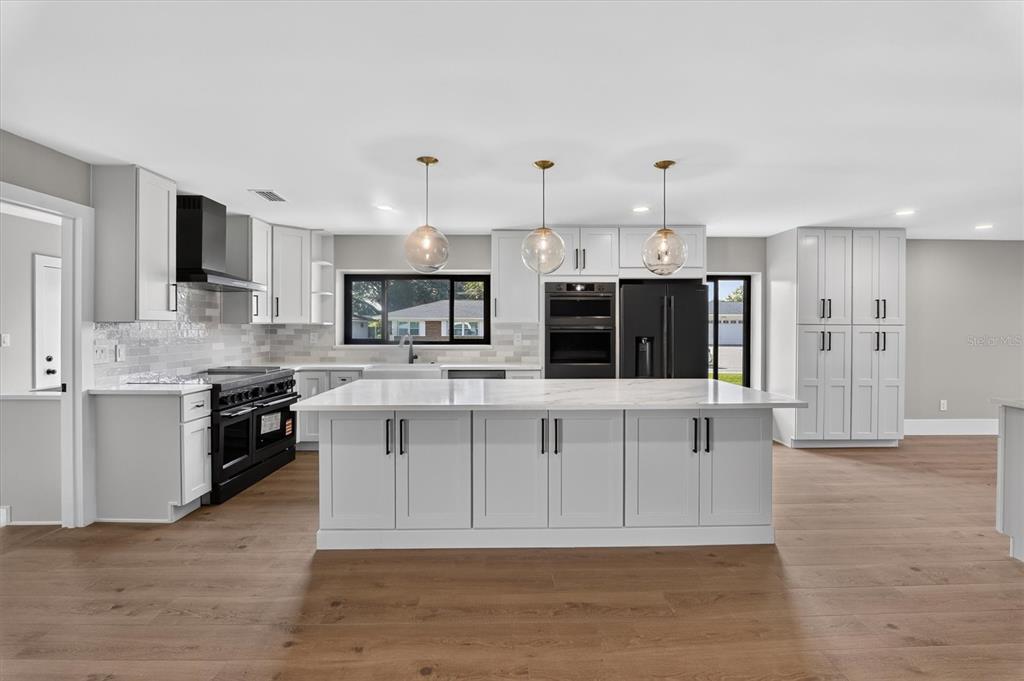 A modern kitchen features white cabinetry, a large marble-topped island, and stainless steel appliances — 2491 LAUDER DRIVE, MAITLAND, FL