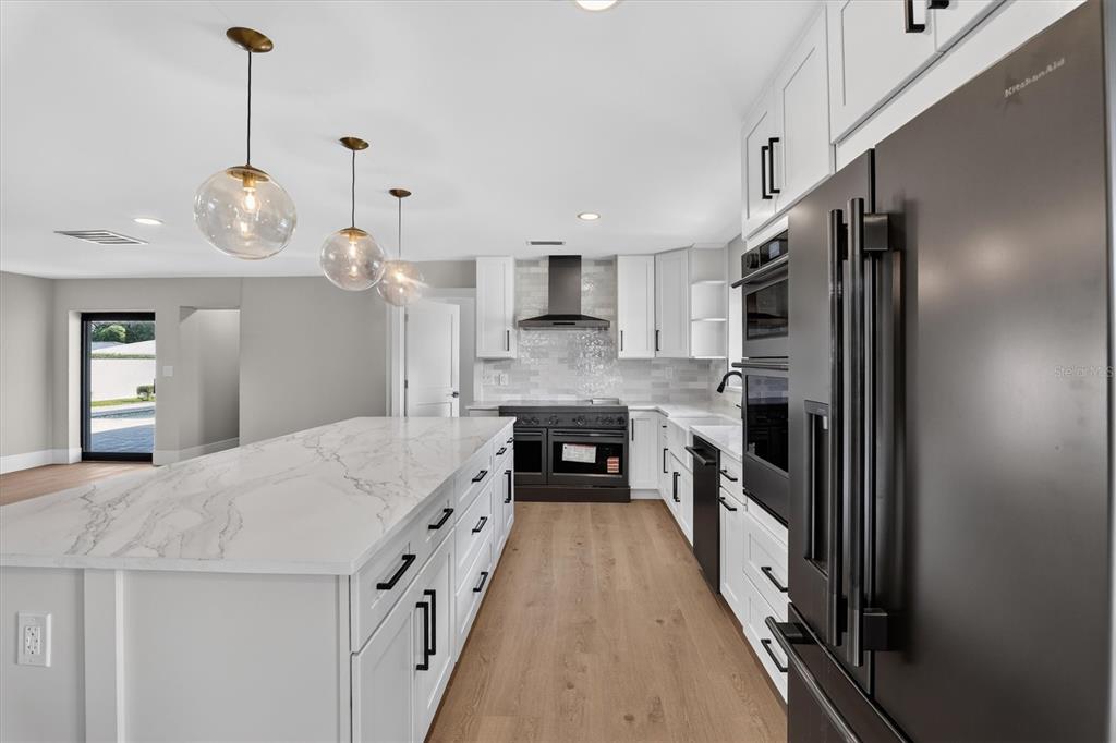 An open-concept living area features a kitchen with an island and a black fireplace — 2491 LAUDER DRIVE, MAITLAND, FL