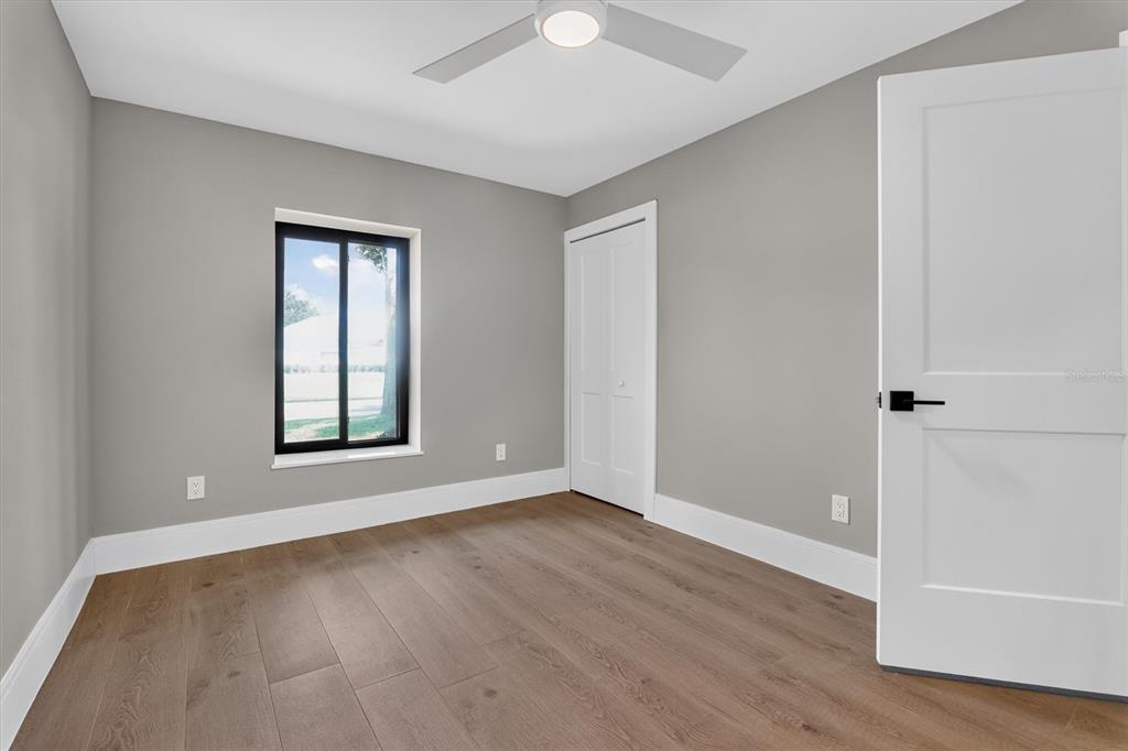 An open-concept living area features light wood flooring, a modern chandelier, and a white kitchen — 2491 LAUDER DRIVE, MAITLAND, FL