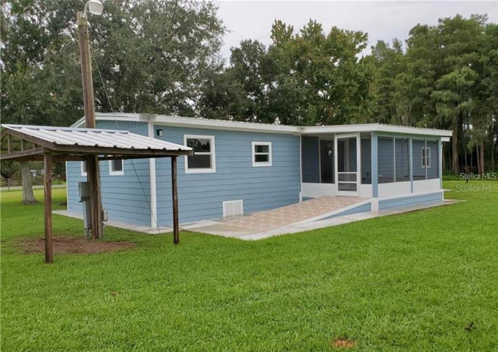 A light blue mobile home with a screened-in porch and a detached metal carport — 3215 TUCKER AVENUE, ST CLOUD, FL