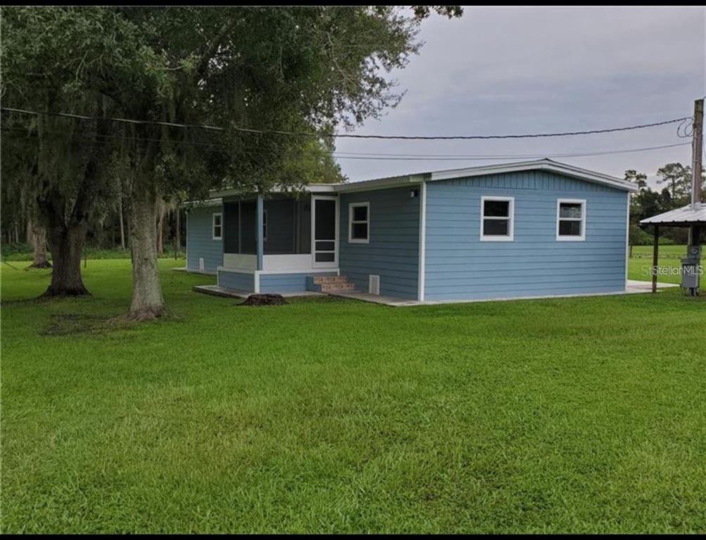 A blue single-story manufactured home with a screened-in porch sits on a grassy lot — 3215 TUCKER AVENUE, ST CLOUD, FL