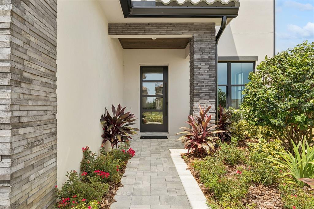 A two-story house features a stone-veneer garage, a tiled roof, and a glass-paneled front door — 15825 VETTA DRIVE, BELLA COLLINA, FL