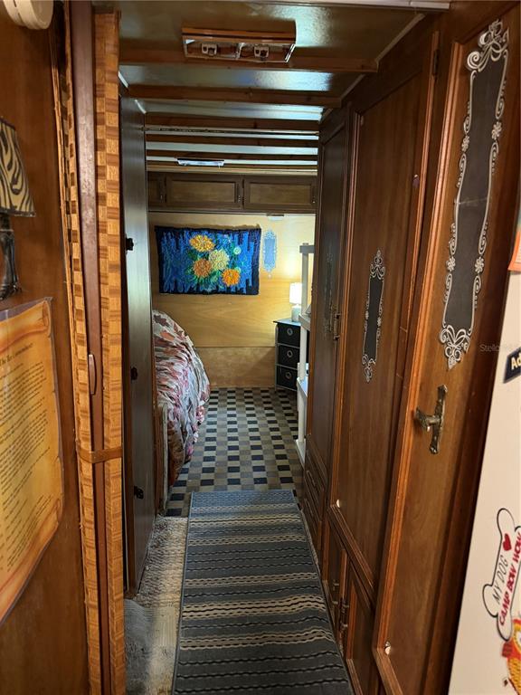 A narrow hallway with wood-paneled walls leads to a bedroom featuring a floral wall hanging — 6521 SE 55TH STREET, OKEECHOBEE, FL