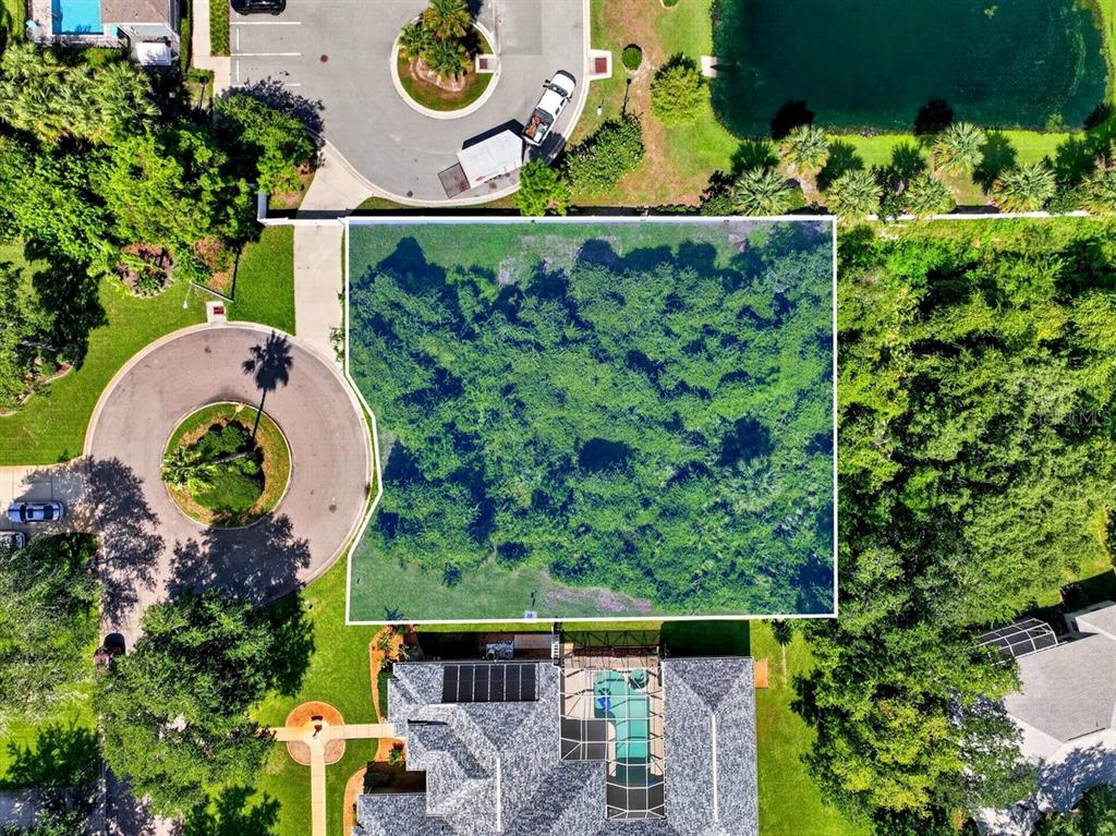An aerial view shows a rectangular, wooded vacant lot situated between a cul-de-sac and a house — 2 DEERSKIN LANE, ORMOND BEACH, FL
