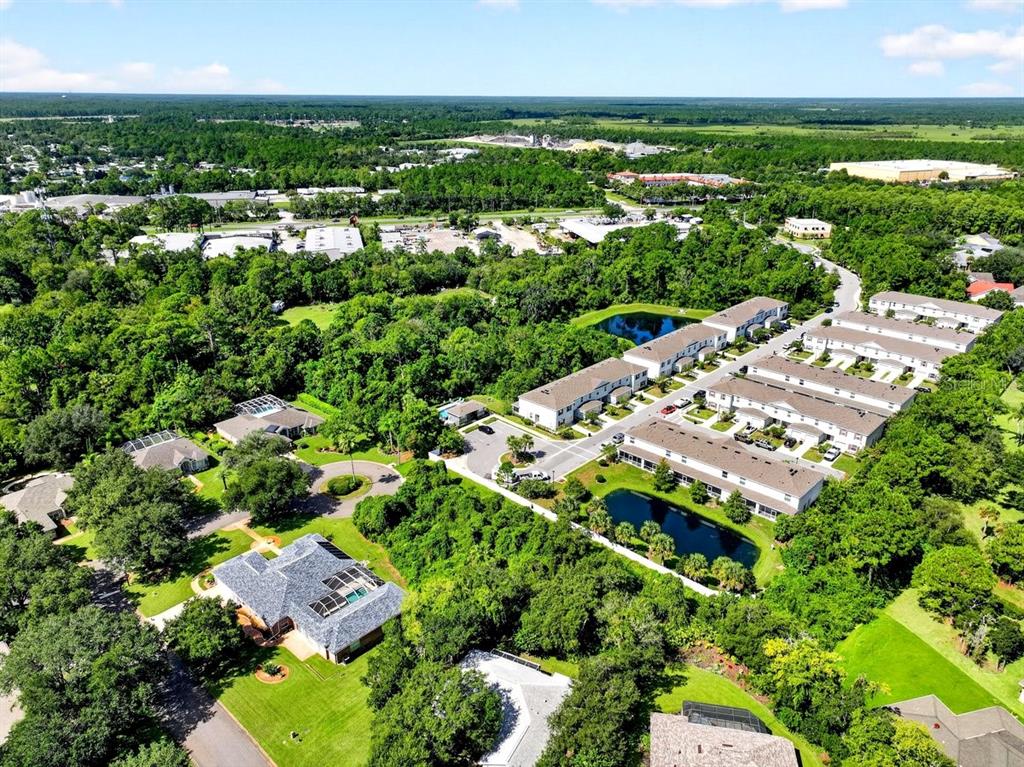 An aerial view shows a residential neighborhood with townhomes, single-family houses, and small ponds — 2 DEERSKIN LANE, ORMOND BEACH, FL