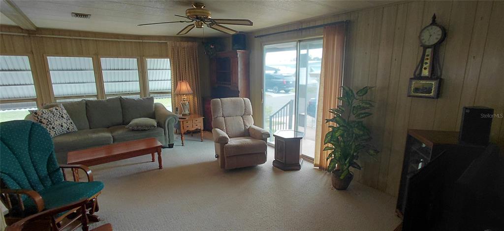 A living room features wood-paneled walls, a ceiling fan, a sofa, and a recliner — 2127 OAHU DRIVE, HOLIDAY, FL