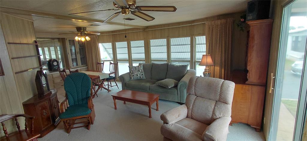 A living room with wood-paneled walls, a ceiling fan, a sofa, and a recliner — 2127 OAHU DRIVE, HOLIDAY, FL