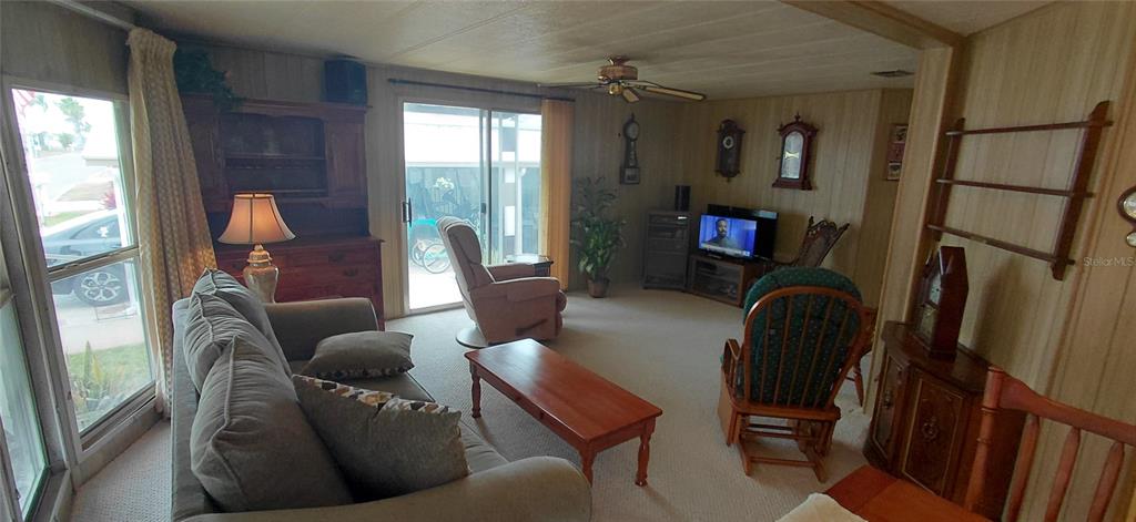 A living room features wood-paneled walls, a gray sofa, a coffee table, and a recliner — 2127 OAHU DRIVE, HOLIDAY, FL