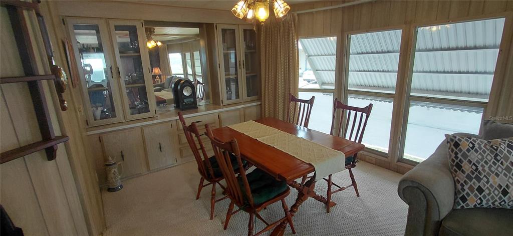 A dining area features wood-paneled walls, a wooden table with four chairs, and built-in cabinetry — 2127 OAHU DRIVE, HOLIDAY, FL
