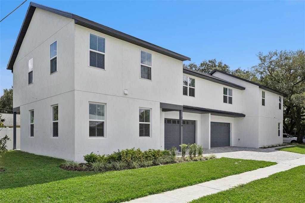 A two-story white stucco duplex with gray garage doors and a paved driveway — 2119 W LUCERNE TERRACE, ORLANDO, FL