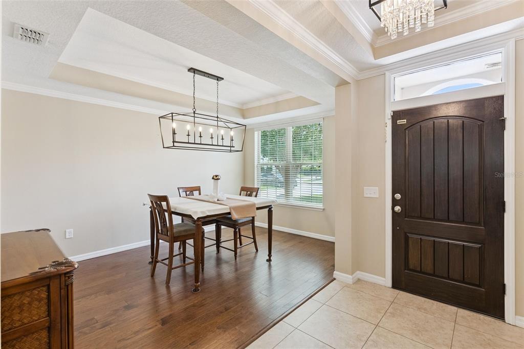 A dining area with wood floors, a rectangular chandelier, and an adjacent entryway with tile — 8701 IRON MOUNTAIN TRAIL, WINDERMERE, FL
