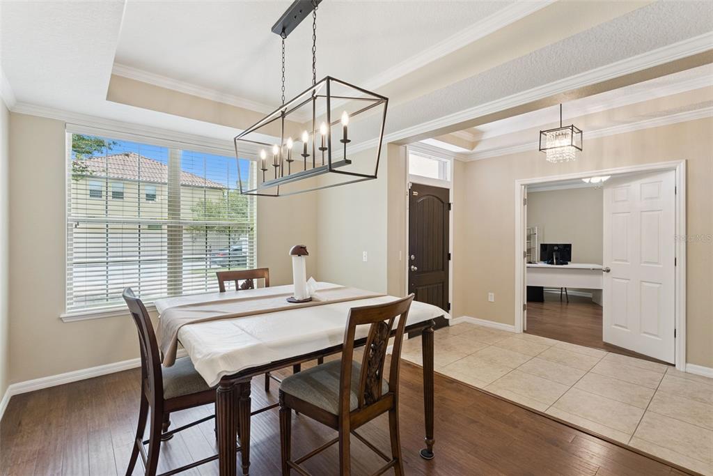 A dining room with a rectangular chandelier, wooden table, and an adjacent office through doors — 8701 IRON MOUNTAIN TRAIL, WINDERMERE, FL